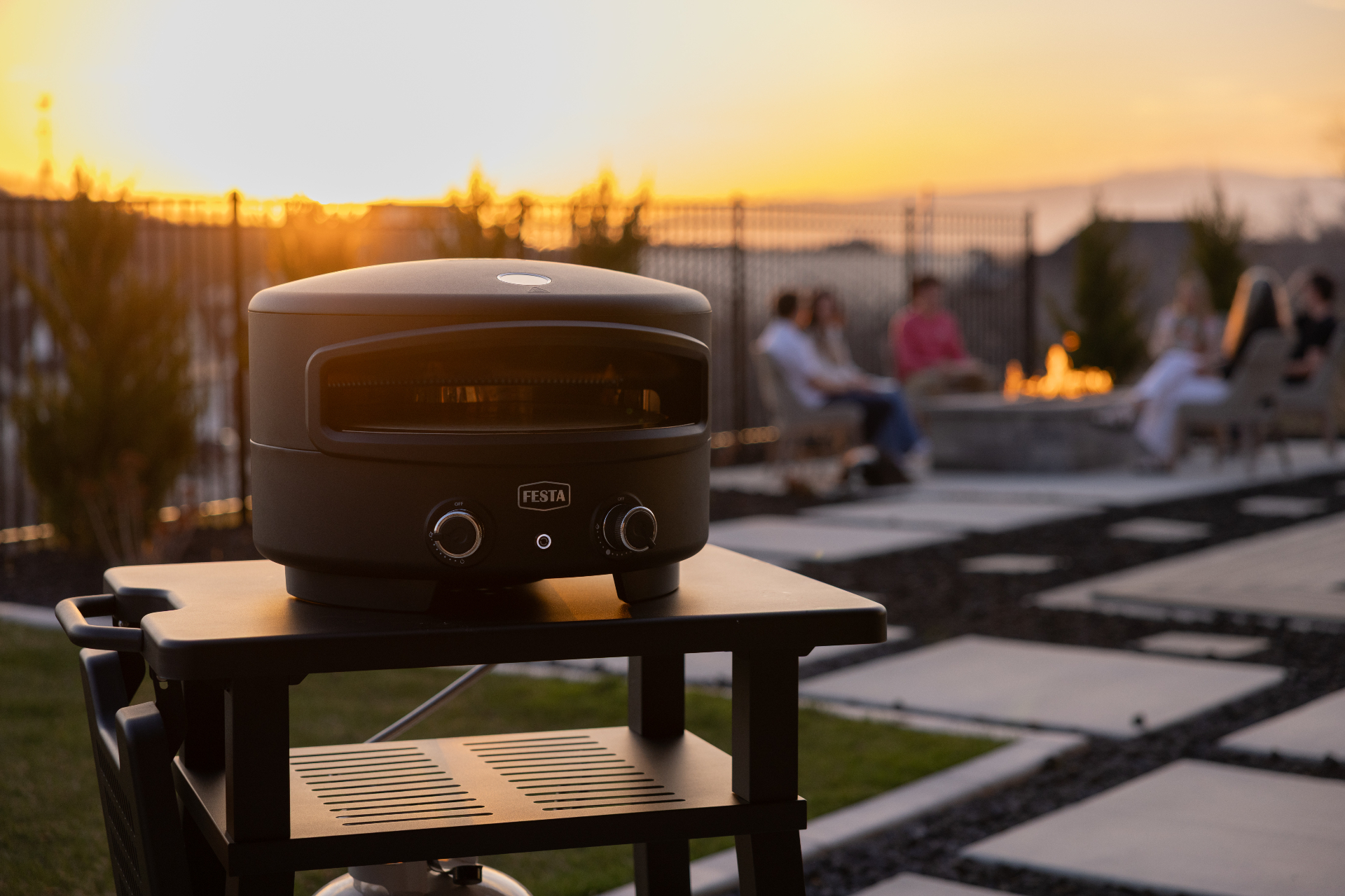 Family gathered around a Festa pizza oven at sunset